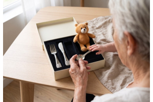 Grossmutter hält den Löffel eines Berndorf Carino Kinderbestecks, die Hand eines Babys greift danach